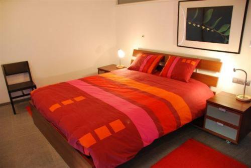 a bedroom with a large bed with a red and orange blanket at Aparthotel Malpertuus in Aalst