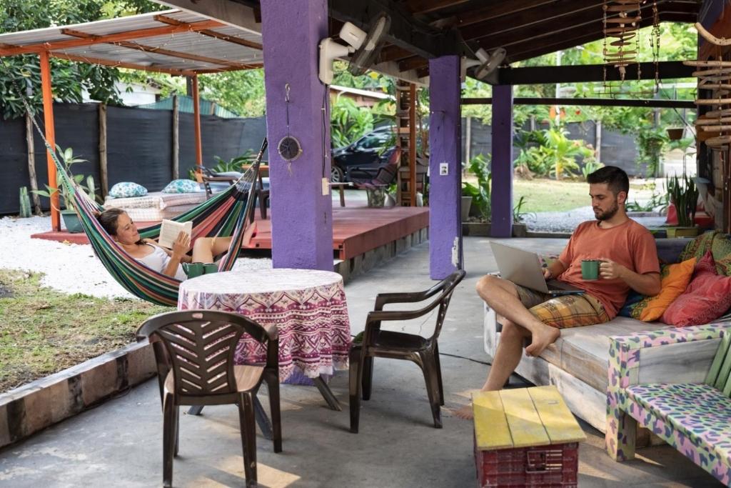 a man sitting in a hammock with a laptop at Passiflora Backpackers Samara in Sámara