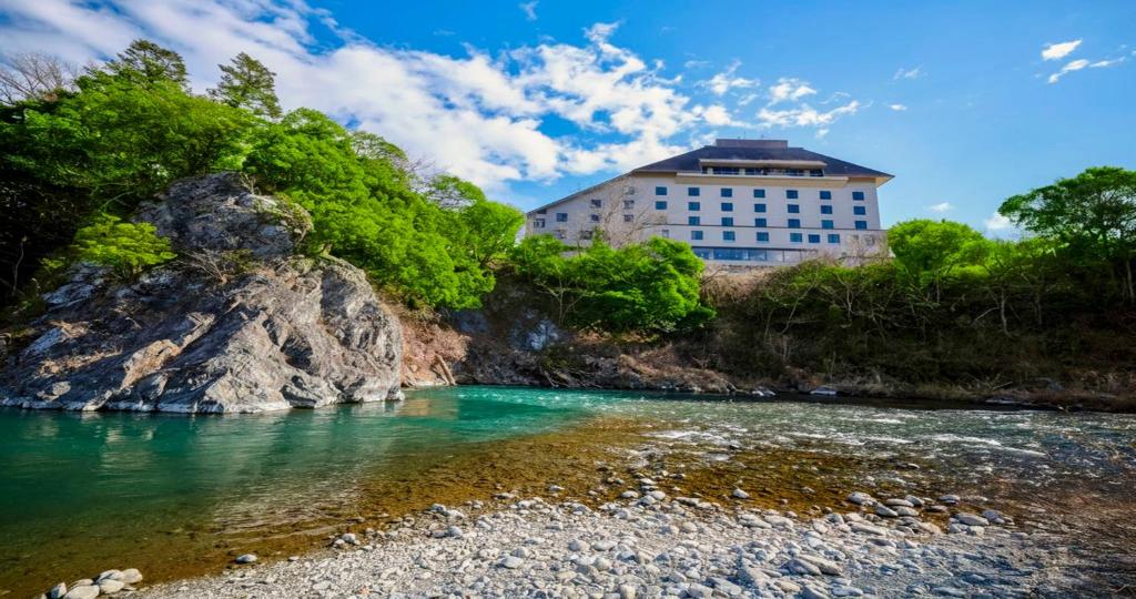 a building on a hill next to a river at KAMENOI HOTEL Ome in Ome