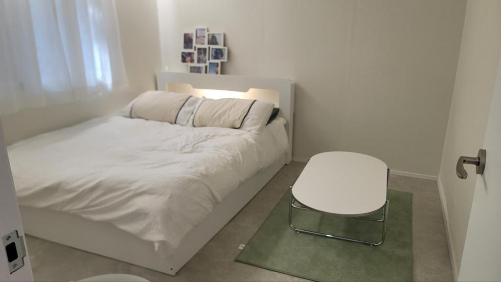 a small bedroom with a white bed and a stool at 모던한 스테이 in Samgong