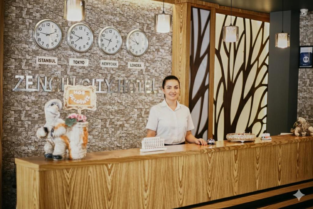 a man standing at a counter in a room with clocks at Zengin City Hotel in Istanbul