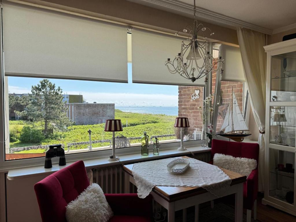 a dining room with a table and a large window at Langeneß Whg 15 Strandtraum in Wyk auf Föhr