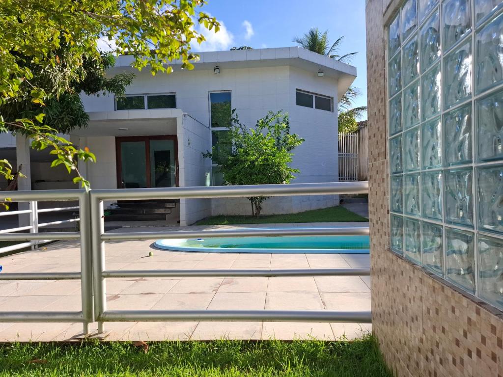 a house with a swimming pool and a fence at Suíte Tranquila em Ambiente Familiar em Antares in Maceió