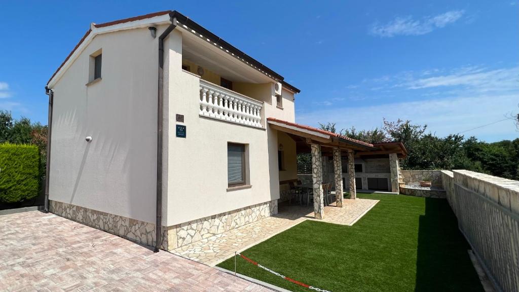 a white house with a yard with green grass at Apartment House Liznjan in Ližnjan