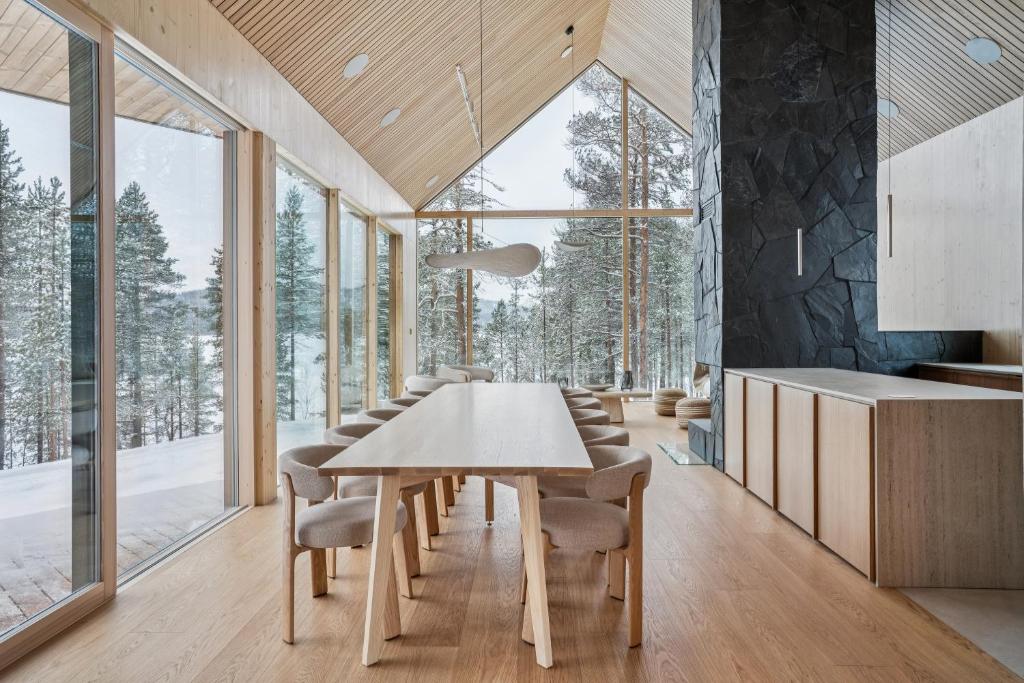 a dining room with a table and chairs and windows at Inai Haven in Ivalo
