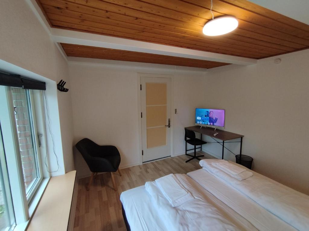 ein Schlafzimmer mit zwei Betten und einem Schreibtisch mit Fernseher in der Unterkunft Fjeldgaard - Aarup in Årup