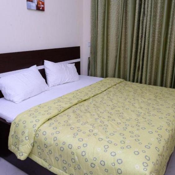 a bedroom with a bed with a yellow comforter at Safari lodge in Udawalawe
