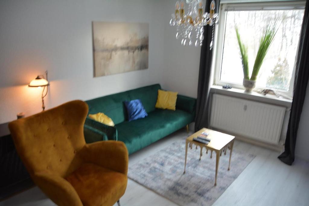 a living room with a green couch and a chair at Appartement am Diemelsee Infrarotsauna inklusive in Marsberg