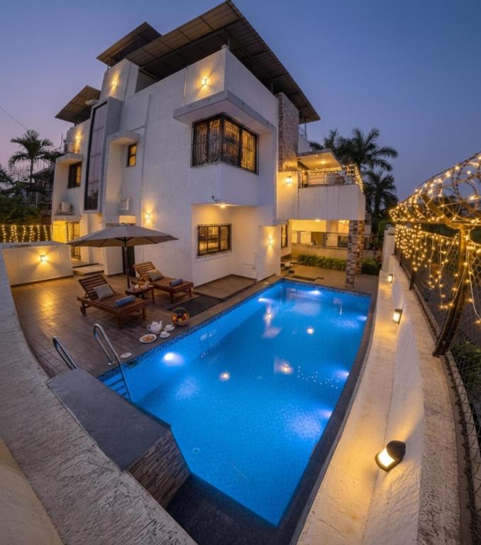 a villa with a swimming pool in front of a house at Aarna Villa nr Valvan Dam in Lonavala