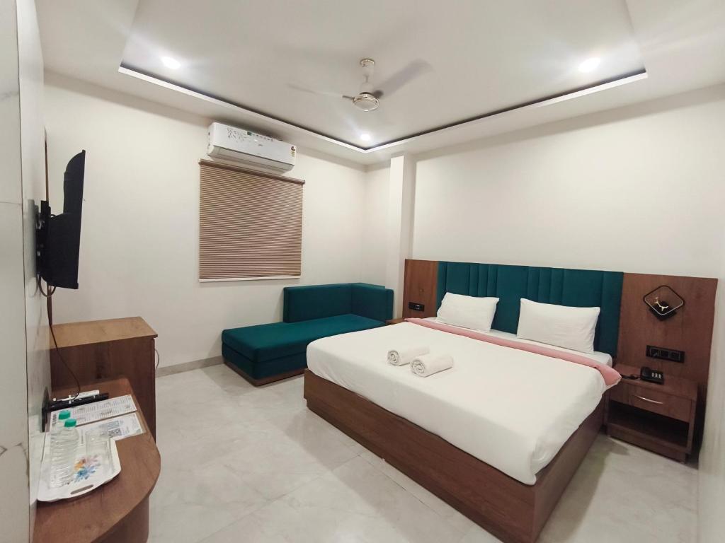 a bedroom with a bed and a blue chair at Hotel Gurukripa in Ujjain