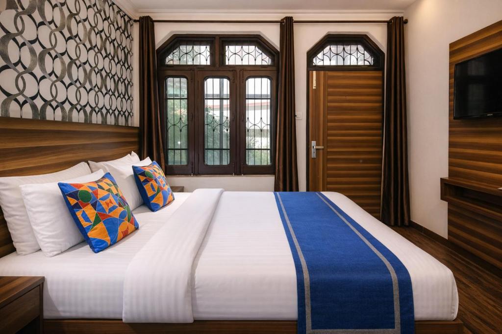 a bedroom with a large bed with blue and white pillows at Hotel Vijay Palace Dharamshala Himachal in Dharmsāla