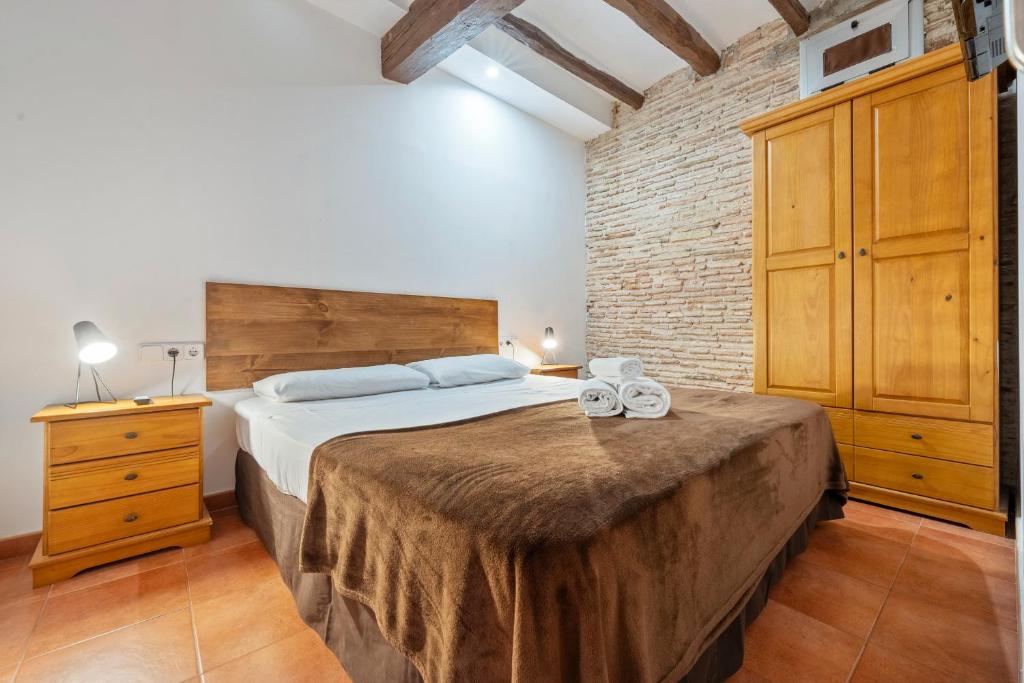 a bedroom with a large bed and a brick wall at Portal del Carro 7 Junto a la Catedral in Tarragona