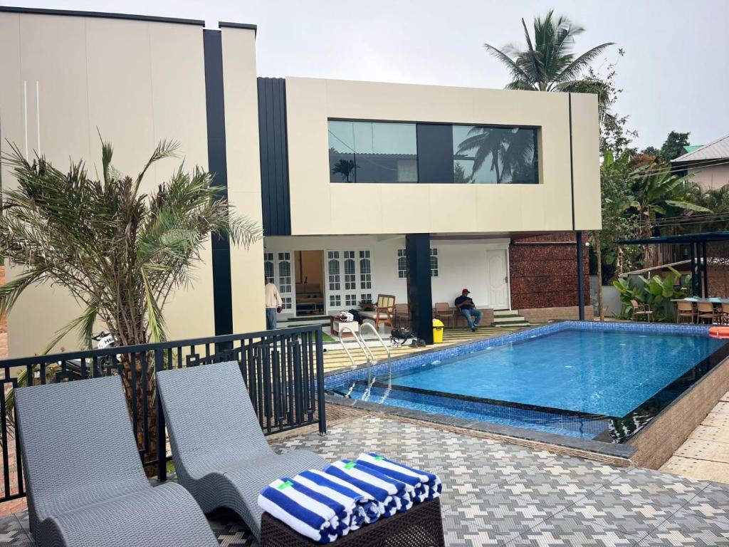 a swimming pool with two chairs and a house at Bumblebee Pool Villa Munnar in Anachal