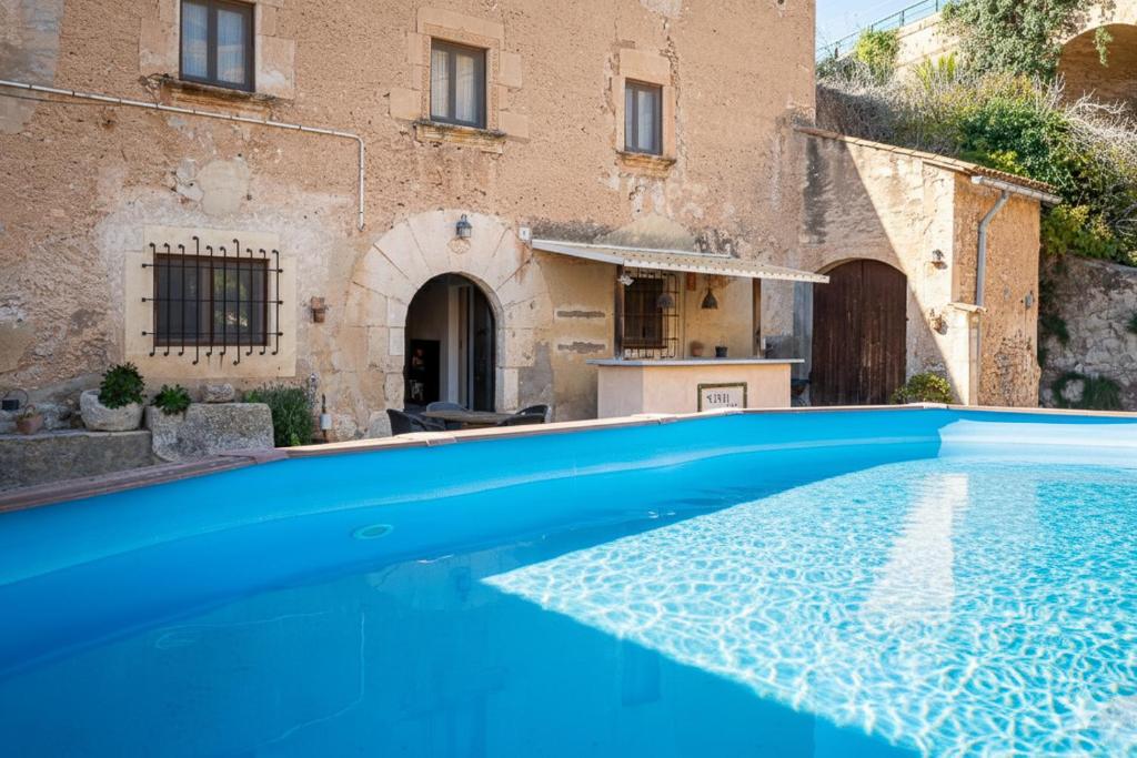 a blue swimming pool in front of a building at AT504 Rustic house with private pool in Roda de Bará