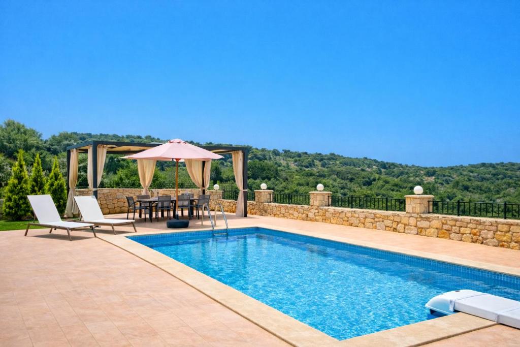 a swimming pool with a table and an umbrella at Natural view villa with private pool in Skouloúfia
