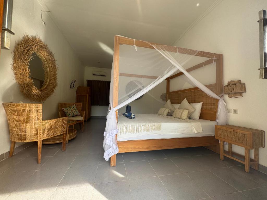a bedroom with a canopy bed and a chair at Blue EmOcean Dive Eco lodge in Moyo Island