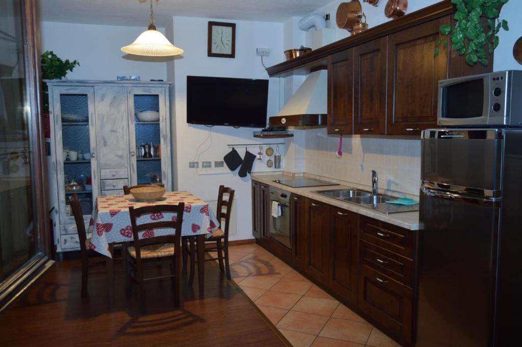 a kitchen with a table with chairs and a refrigerator at Casa Alpina Place in Isolaccia