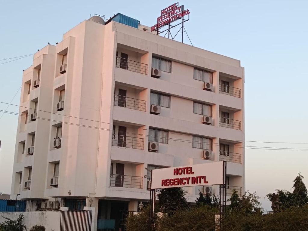 a pink building with a sign in front of it at Hotel Regency International in Jamnagar