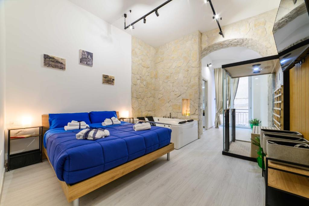 a bedroom with a blue bed and a bathroom at Salerno Mare e Luci Suite in Salerno