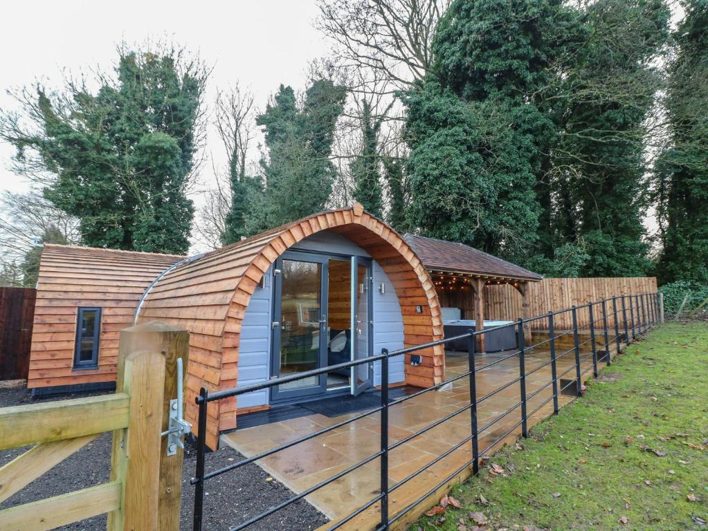 a small house with a wooden roof and a fence at Park View Lodge in Derby
