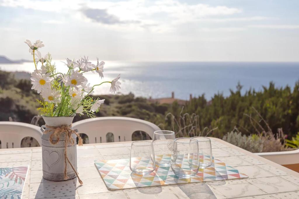 a table with two glasses and a vase with flowers at Villa K1- INFINITYHOLIDAYS in Costa Paradiso