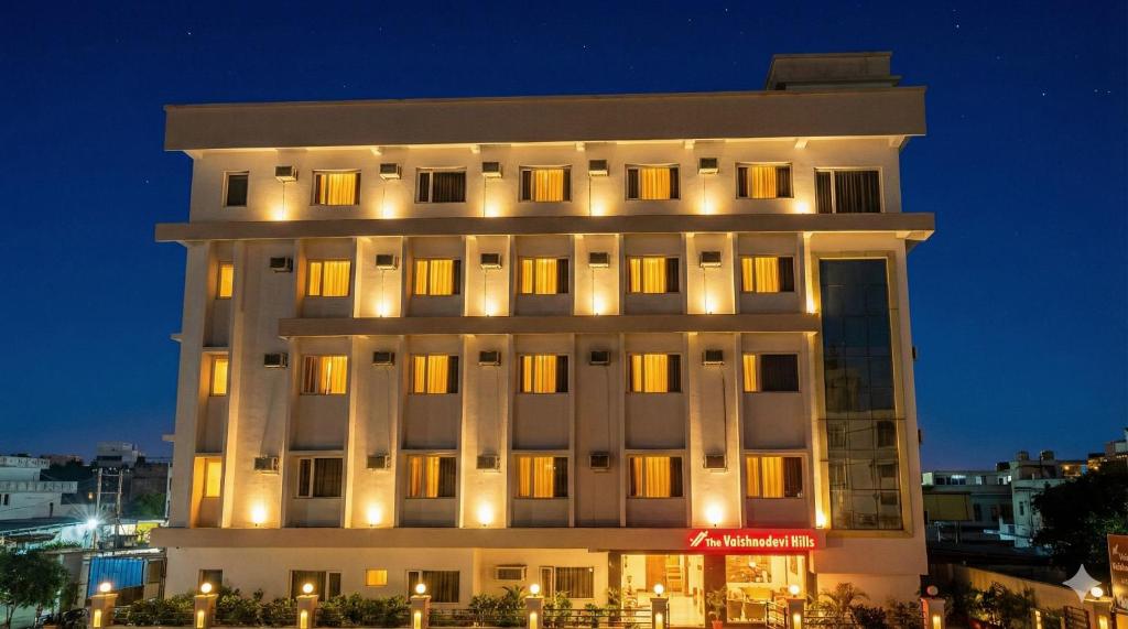 a large white building with lights on it at night at Hotel The Vaishno Devi Hills in Katra