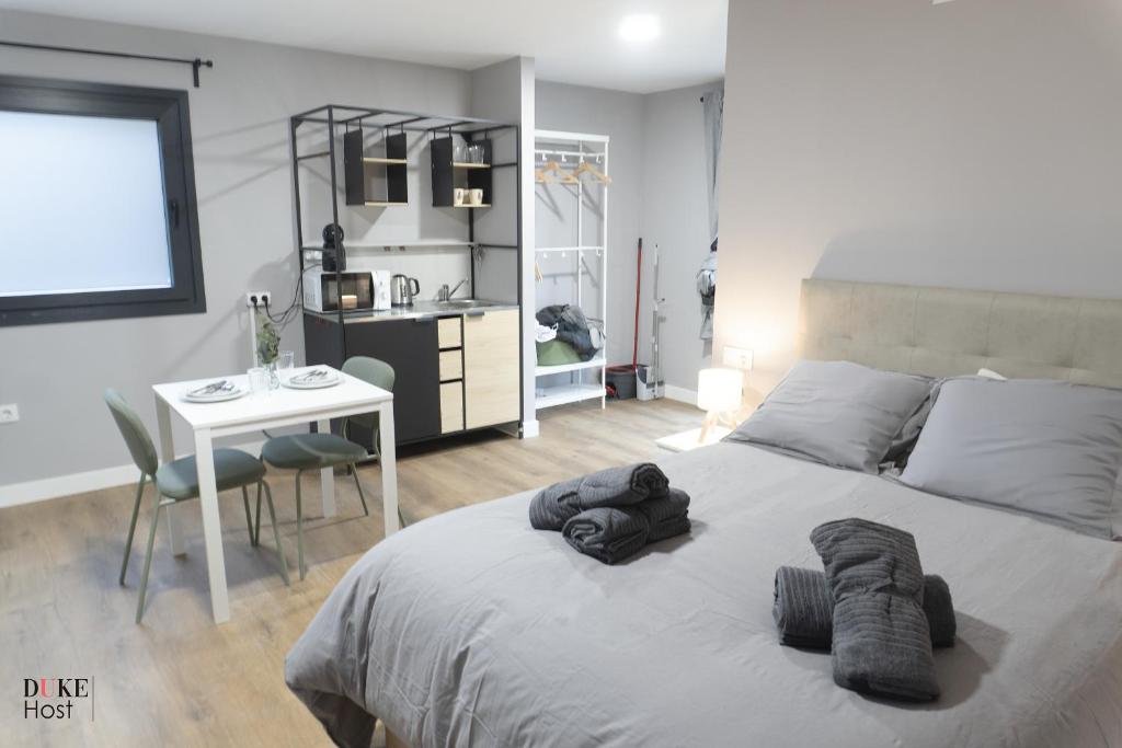 a bedroom with a bed and a table and a kitchen at Sierra de Madrid Suites in Galapagar