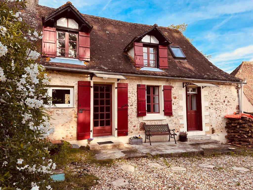 an old house with red doors and a bench at Les Deux Canards Perdus in Rouffignac Saint-Cernin