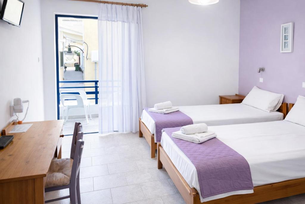 a room with two beds and a desk and a table at Blue Sky in Palaiochora