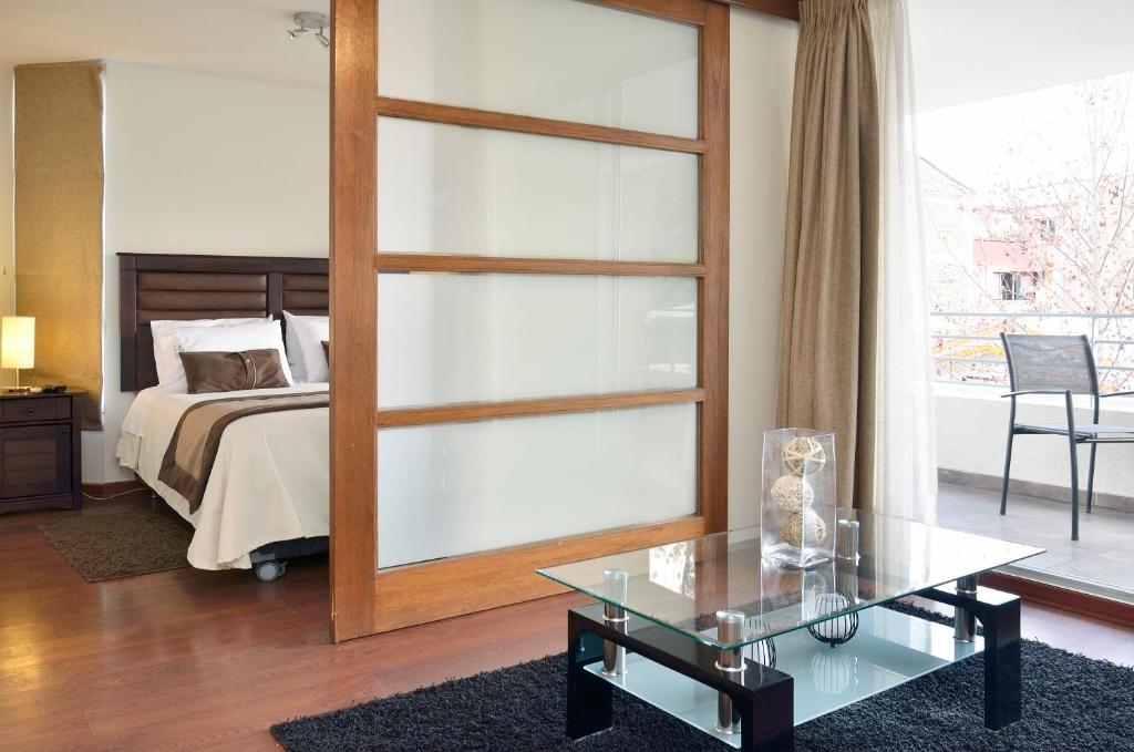 1 dormitorio con cama y mesa de cristal en Norus Providencia, en Santiago