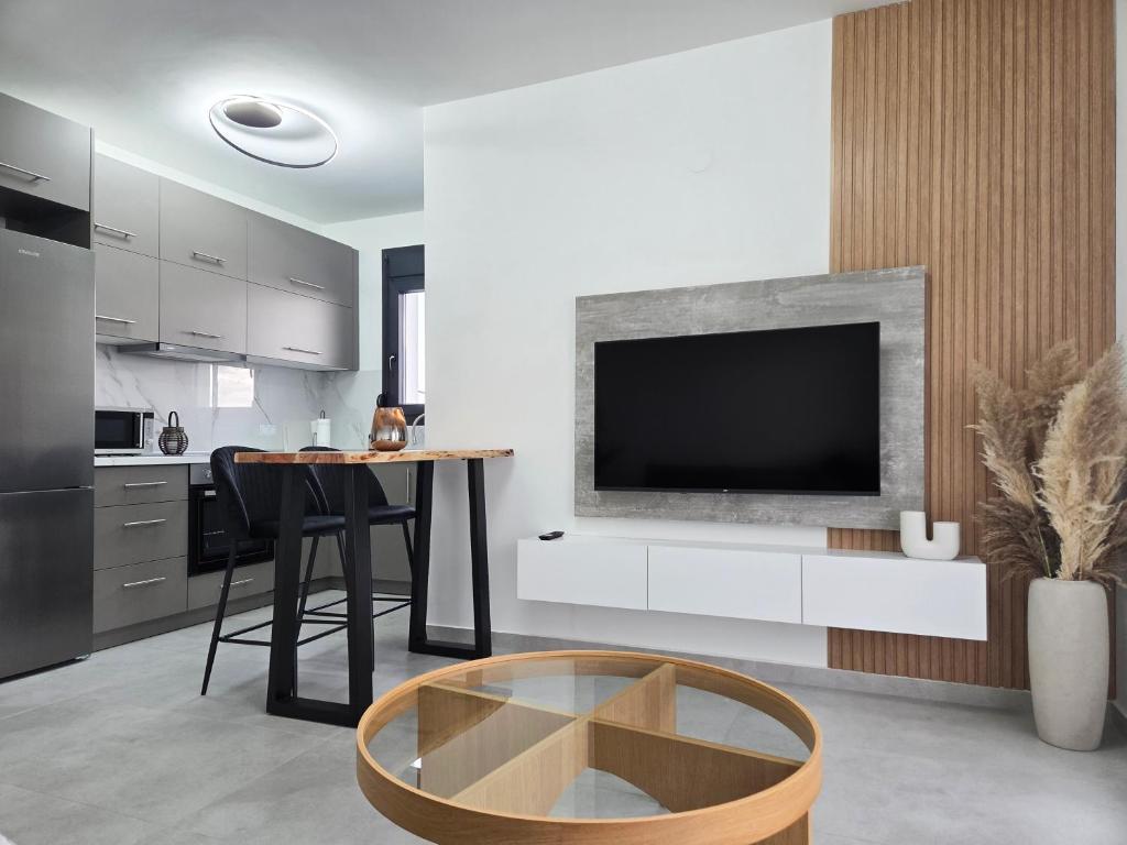 a kitchen with a table and a tv on a wall at Ocaso Luxury Apartment in Nea Peramos