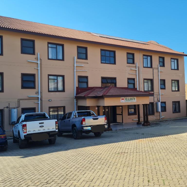 two trucks parked in front of a building at Hlalanathi Lodge - 9 Shepstone Road, Harding in Harding