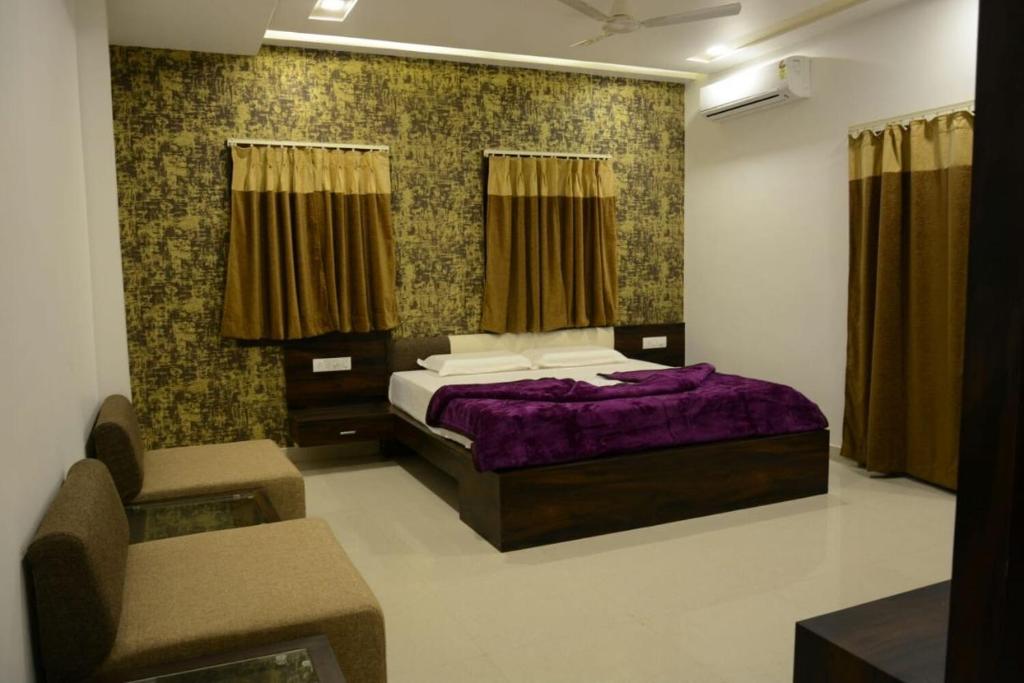 a bedroom with a purple bed and two chairs at Sri Shivam Hotel in Gondia