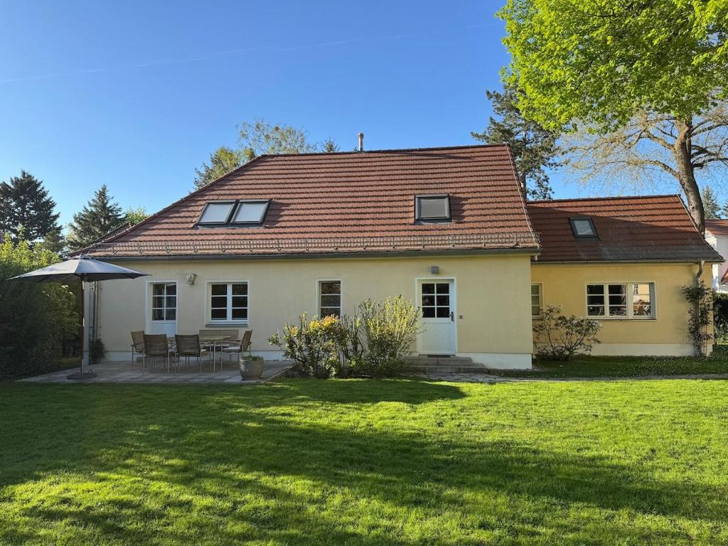 a white house with a table and an umbrella at Cottage in Kleinmachnow