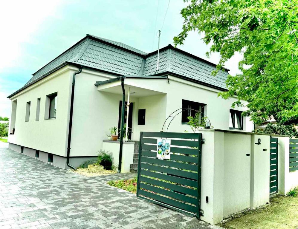 a white house with a gate and a fence at CFS Apartman in Debrecen