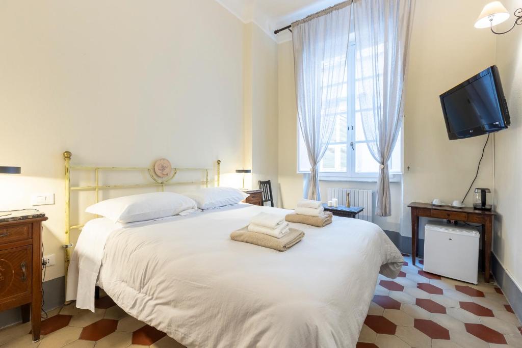 a bedroom with a large white bed with towels on it at Lucca Charm in Lucca