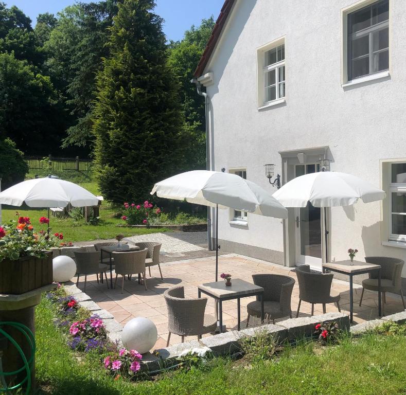 a patio with tables and umbrellas in front of a building at Alte Leimsiederei in Herrnhut