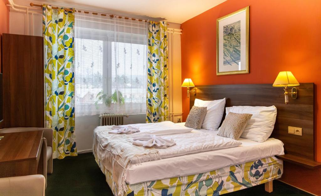 a bedroom with a bed with orange walls and a window at Hotel Formanka in Hustopeče