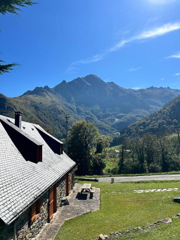 a house with a picnic table and mountains in the background at Le Gîte Escalletas in Arrens-Marsous