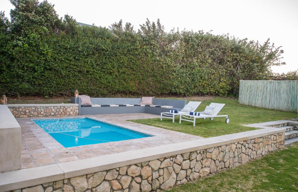 a backyard with a swimming pool and two lounge chairs at Beach House in Struisbaai