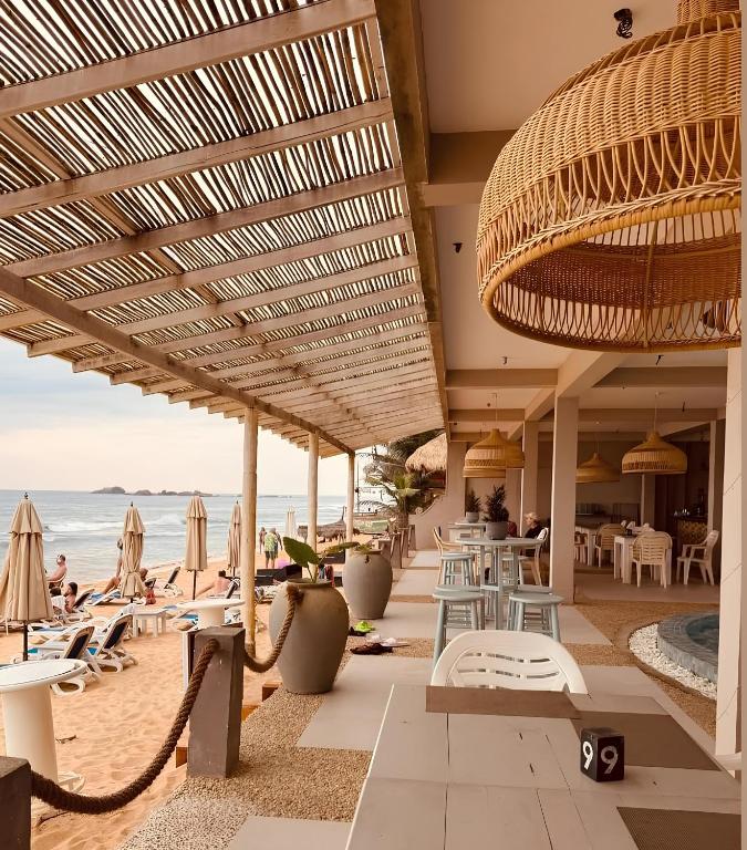 een strand met stoelen, tafels en parasols bij Hotel Blue Note in Hikkaduwa