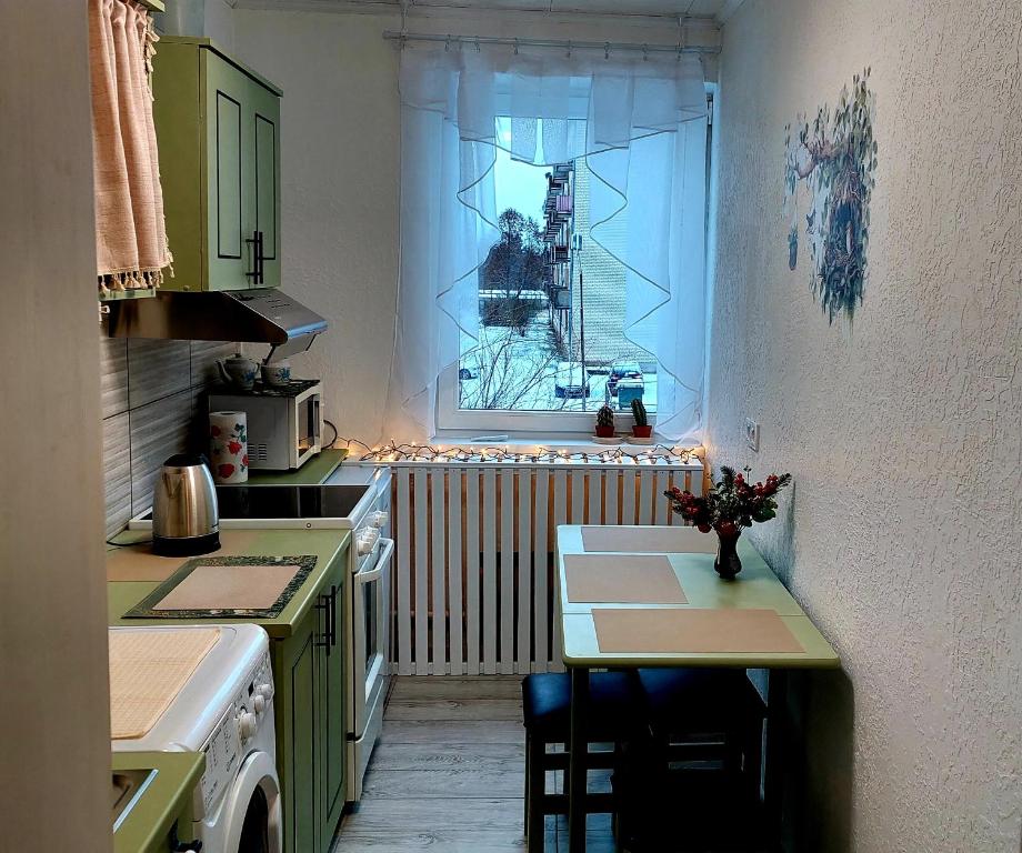 a kitchen with a small table and a window at Ciemos pie Ingas Sedā in Seda