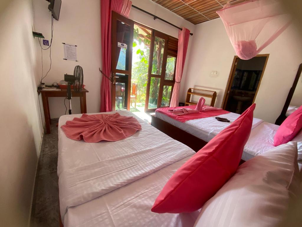 two beds in a room with red pillows at Happiness Cottage in Ella