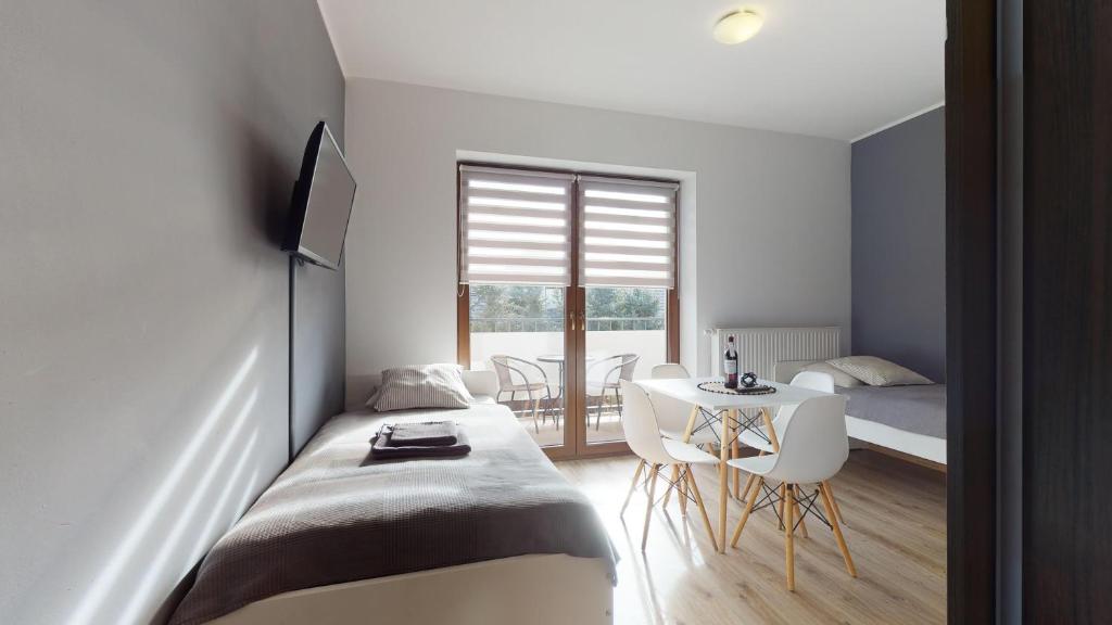 a bedroom with a bed and a table and a window at Apartament Fibra Crema in Rybnik