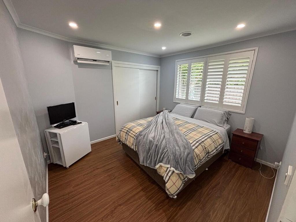 a bedroom with a bed and a television and a window at Guest ensuite room with private entrance in Melbourne