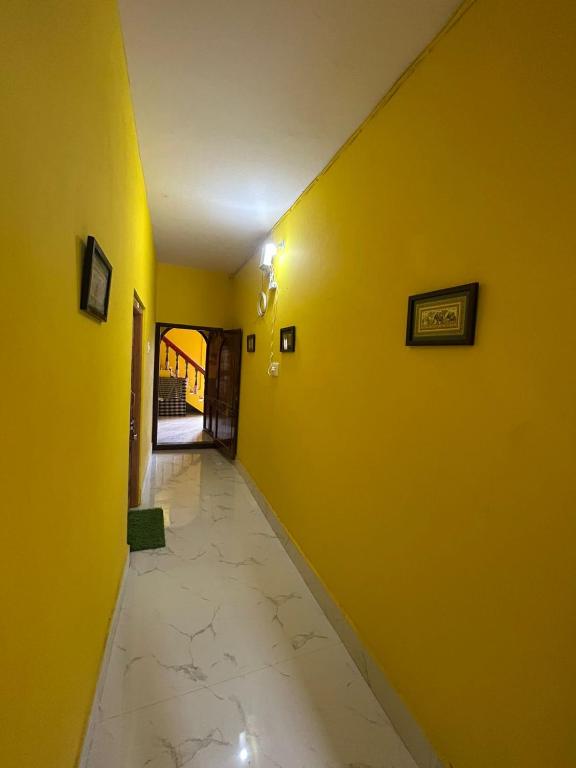 an empty hallway with yellow walls and a tile floor at Hotel Chilika in Bālugān