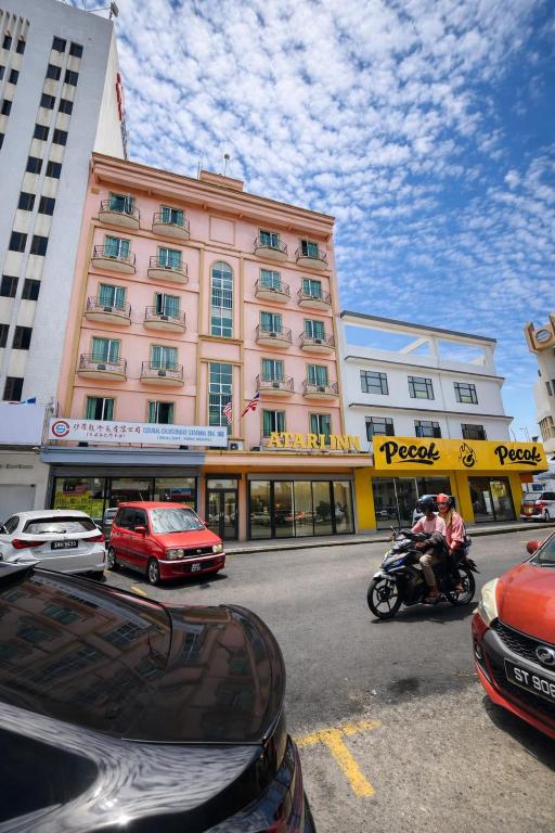 a group of cars parked in front of a pink building at Atari Inn Tawau in Tawau