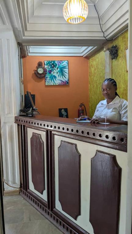 un uomo seduto al bancone di una stanza di NGUELA HoTEL a Yaoundé