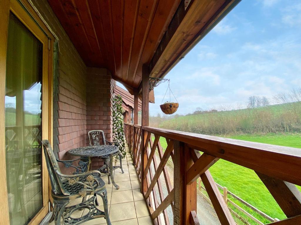 a porch with two chairs and a table on it at Apple-Uk46285 in Camerton