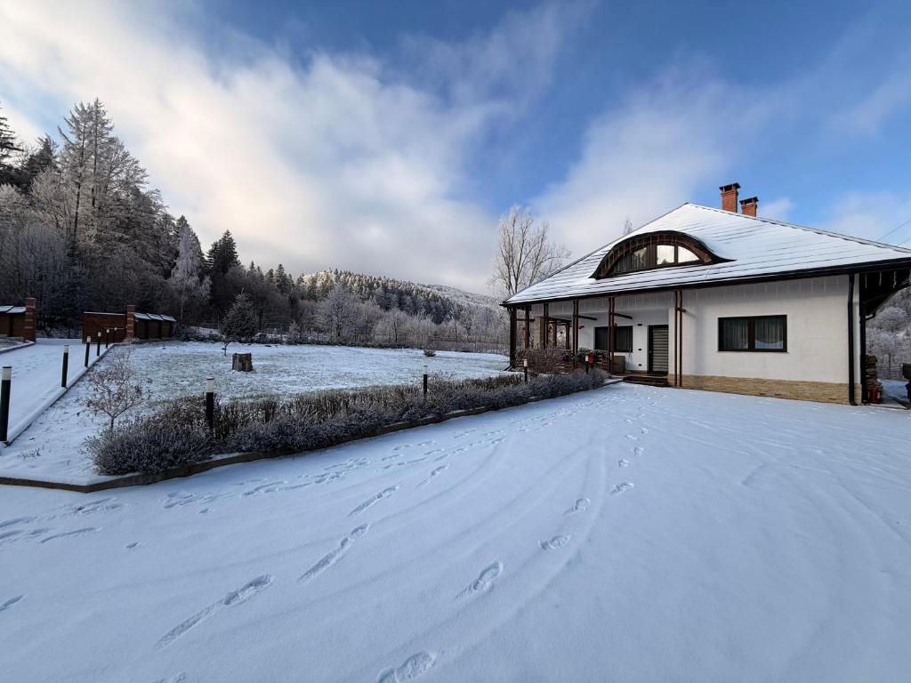 a house covered in snow with footprints in the driveway at Hașca Chalet in Poiana Micului